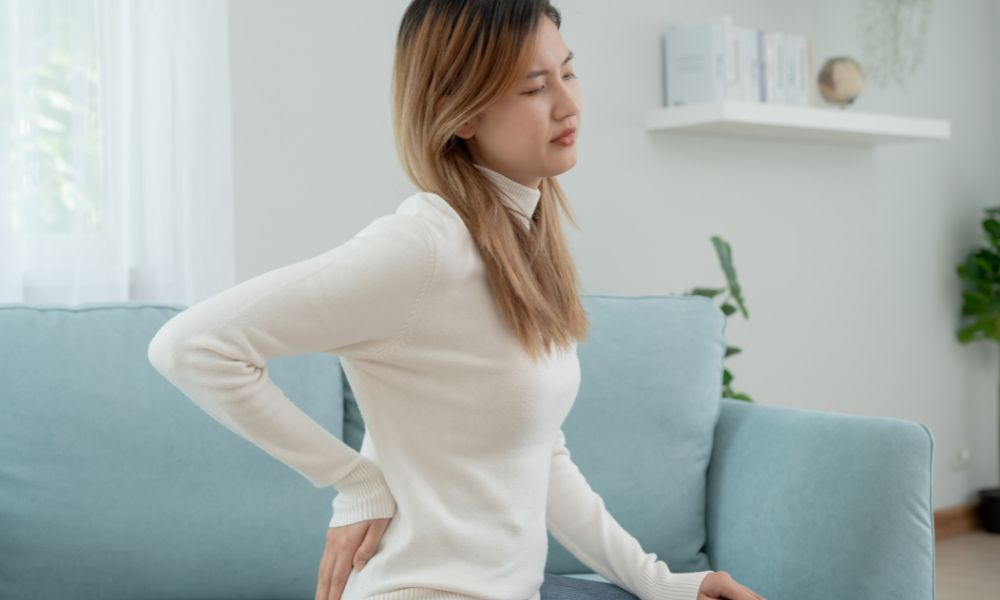 A young woman touching her lower back troubled.