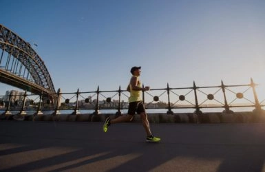 A man jogging in the morning near a bridge.