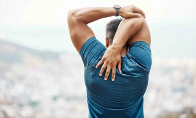 A fit man stretching his shoulders.