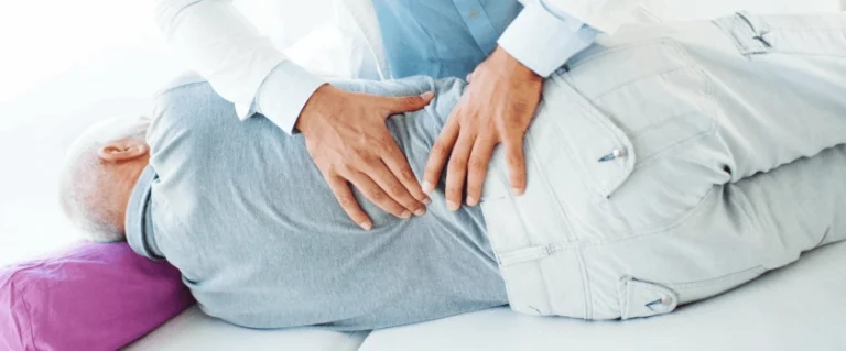 An elderly person lying on their side and having a massage by a chiropractor.