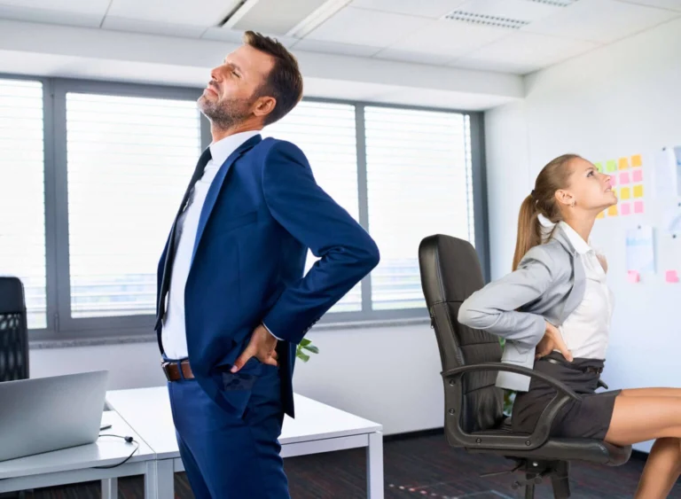 A man and a woman both touching their lower backs in pain.