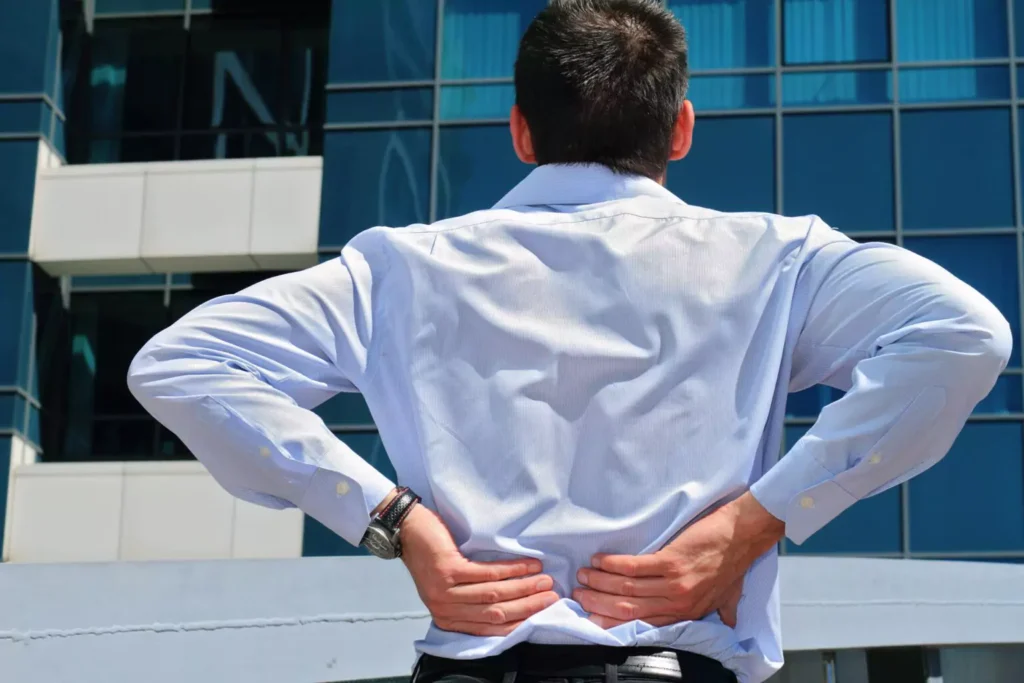 A man touching his lower back with both hands.