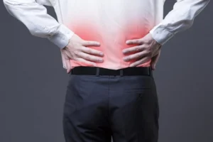 A man touching his lower back in pain.