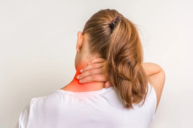 A woman touching her neck in pain.