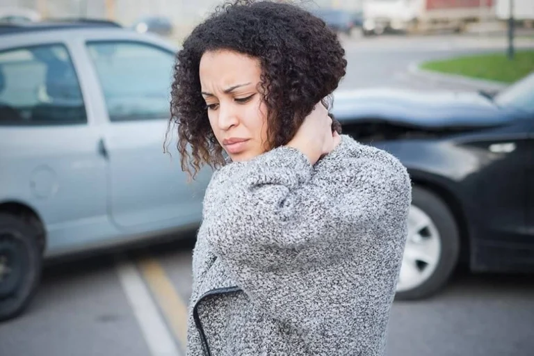 A woman touching her neck in pain.