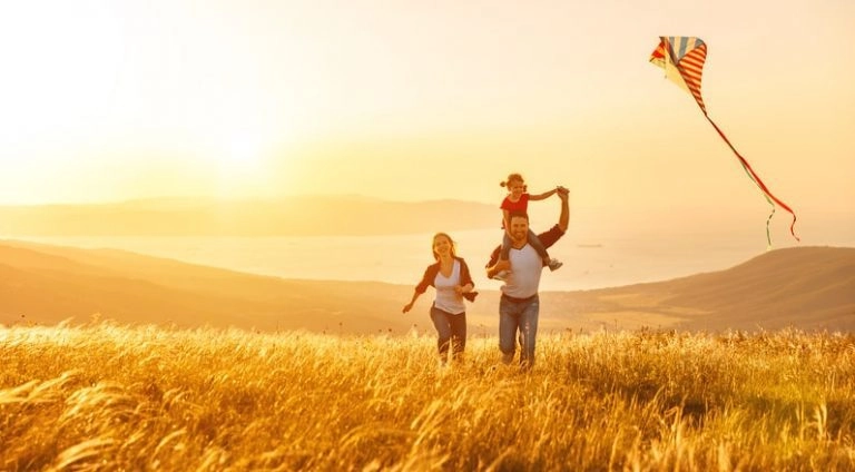 A family running in a field with a kite.