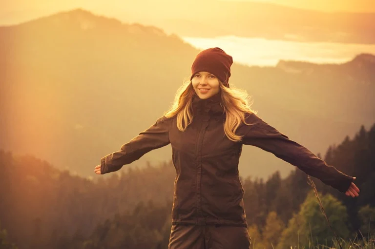 A girl looking happy in front of a mountain range.